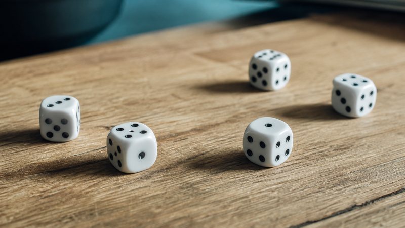 A handful of white dice scattered across a warm wooden tabletop