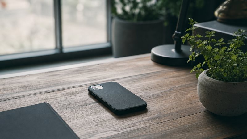 A calm minimalist desk with a phone, plant and daylight, nothing cluttered